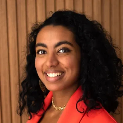 Heba Riyaz Abdulla smiling. She has dark curly hair.